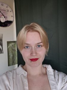 Kuvassa on Helmi Hartikainen. Helmillä on lyhyet vaaleat hiukset ja vaalea kauluspaita.