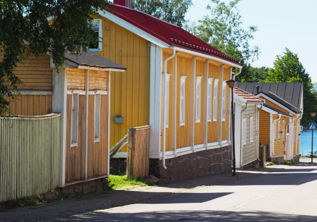 keltainen puinen vanha talo, sininen meri pilkottaa taustalla